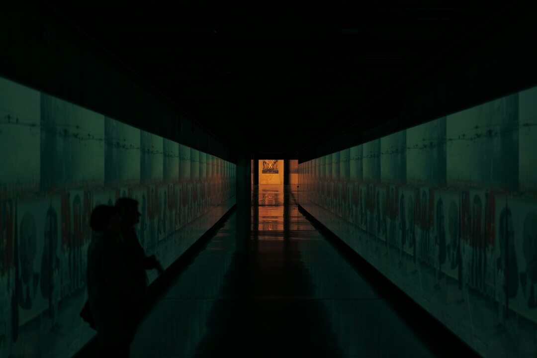 Silhouette of a person walking away down a long museum corridor
