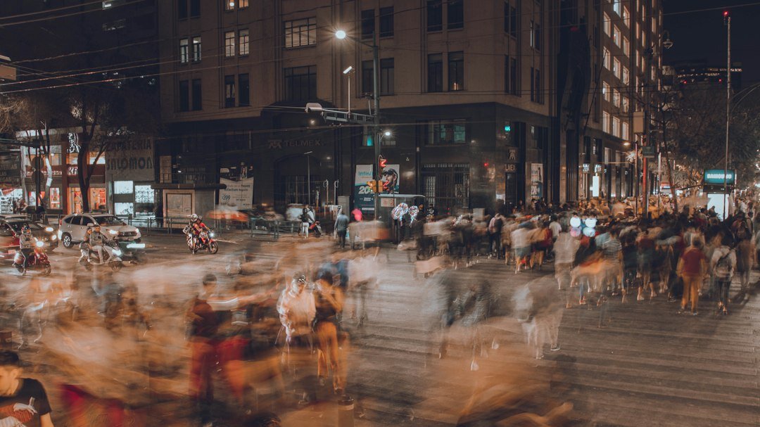 Blurred crowd of people crossing a city street seen from a distance